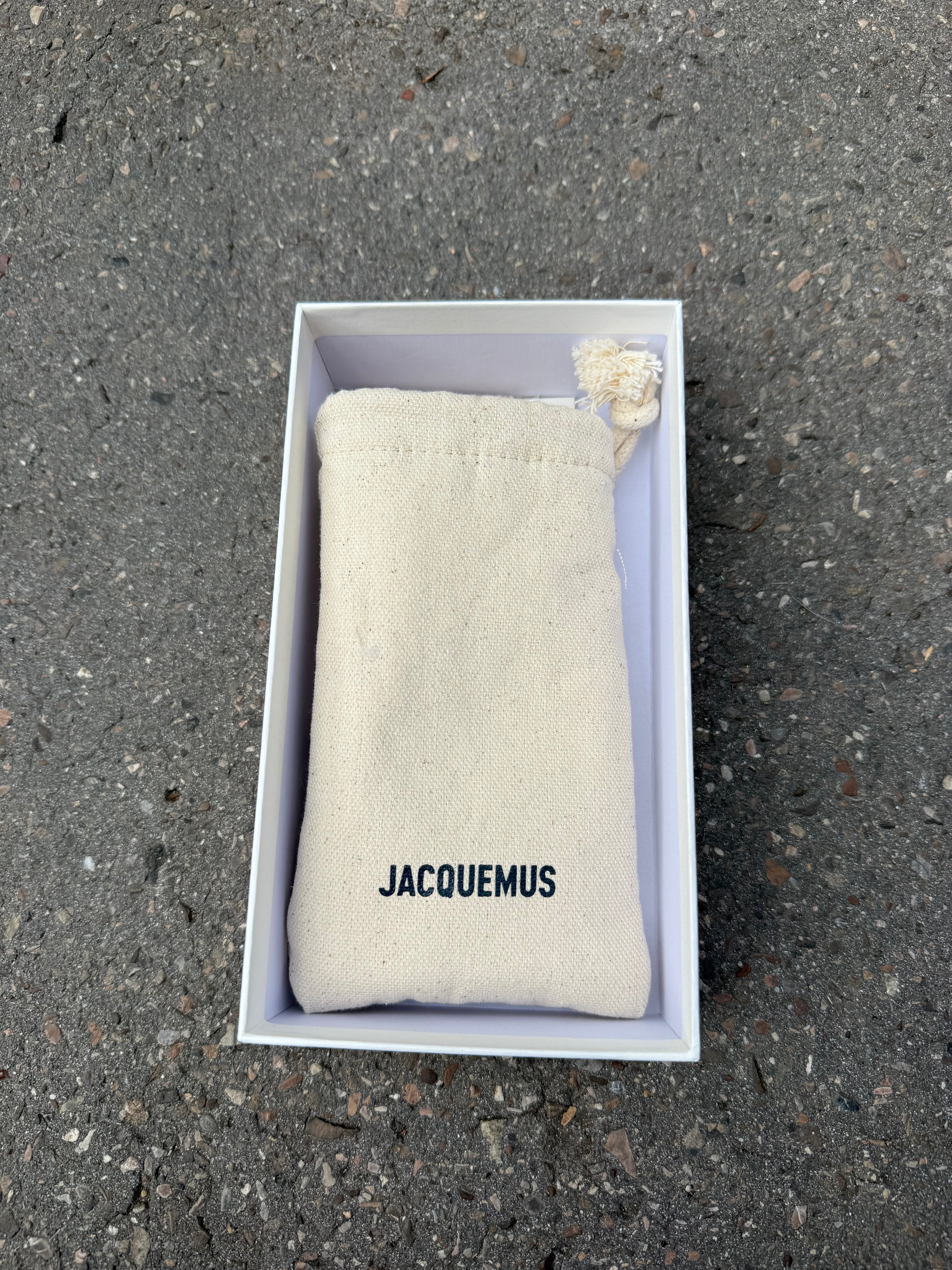 Eine schwarze Sonnenbrille von Jacquemus mit goldenem Schriftzug auf der Seite