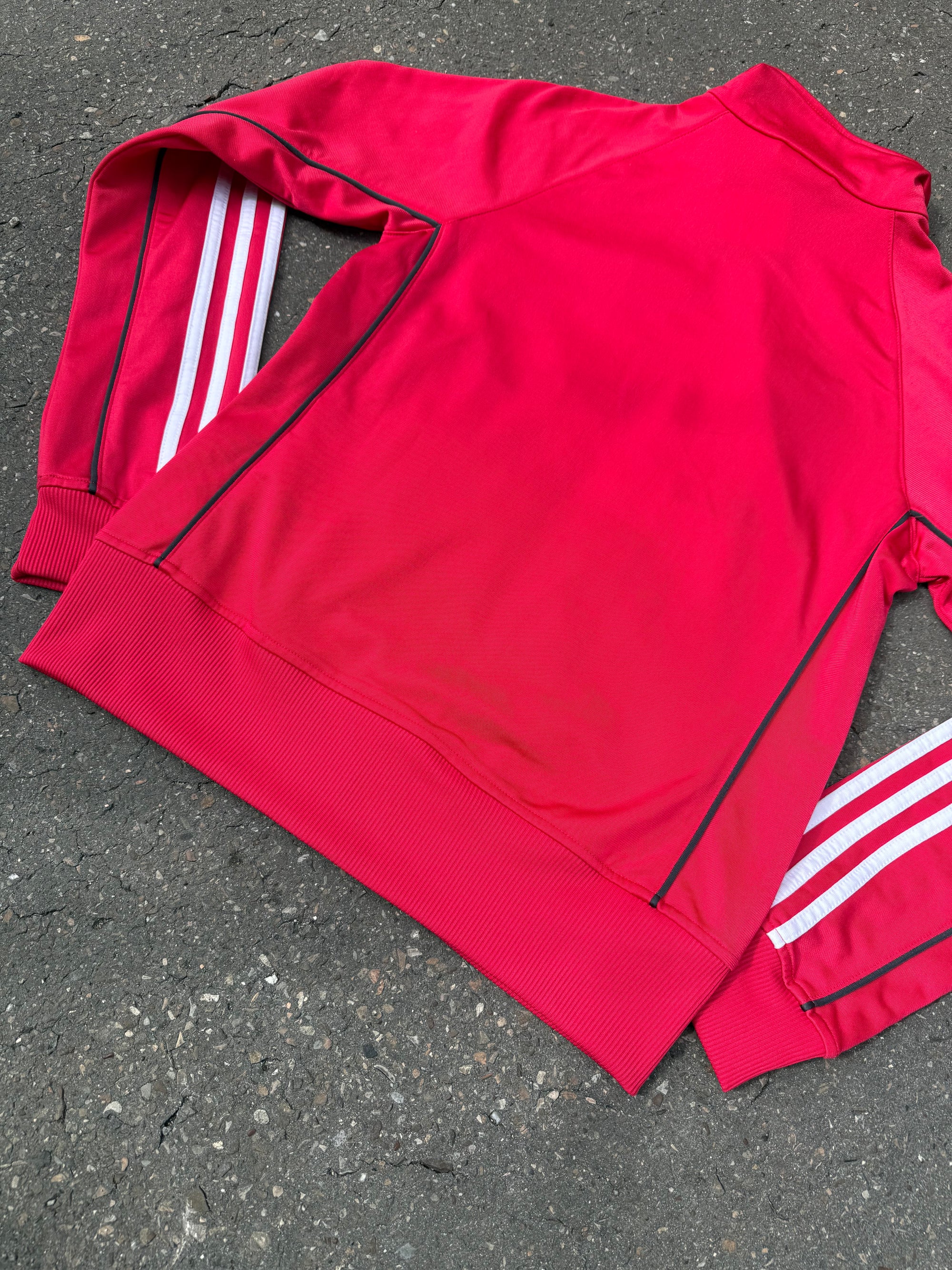 Eine Pinke Trackjacke von Adidas mit weißen Streifen auf den Ärmeln