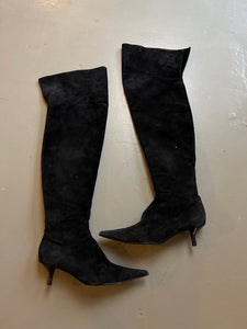Zu sehen sind kniehohe schwarze Stiefel mit dünnen Absätzen von Fendi in Größe 38,5 von der außenSeite vor einem grauen Hintergrund.