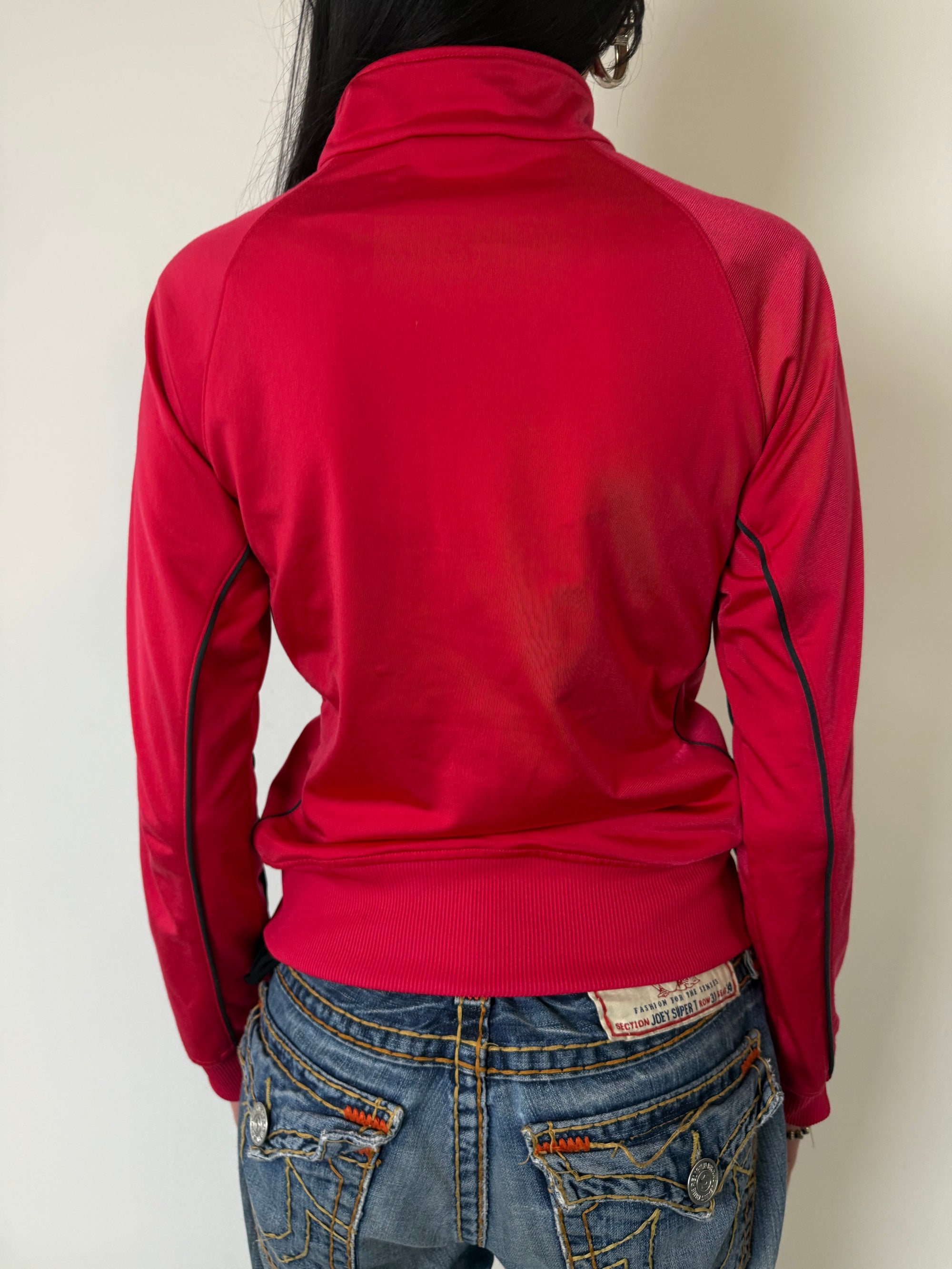 Eine Pinke Trackjacke von Adidas mit weißen Streifen auf den Ärmeln