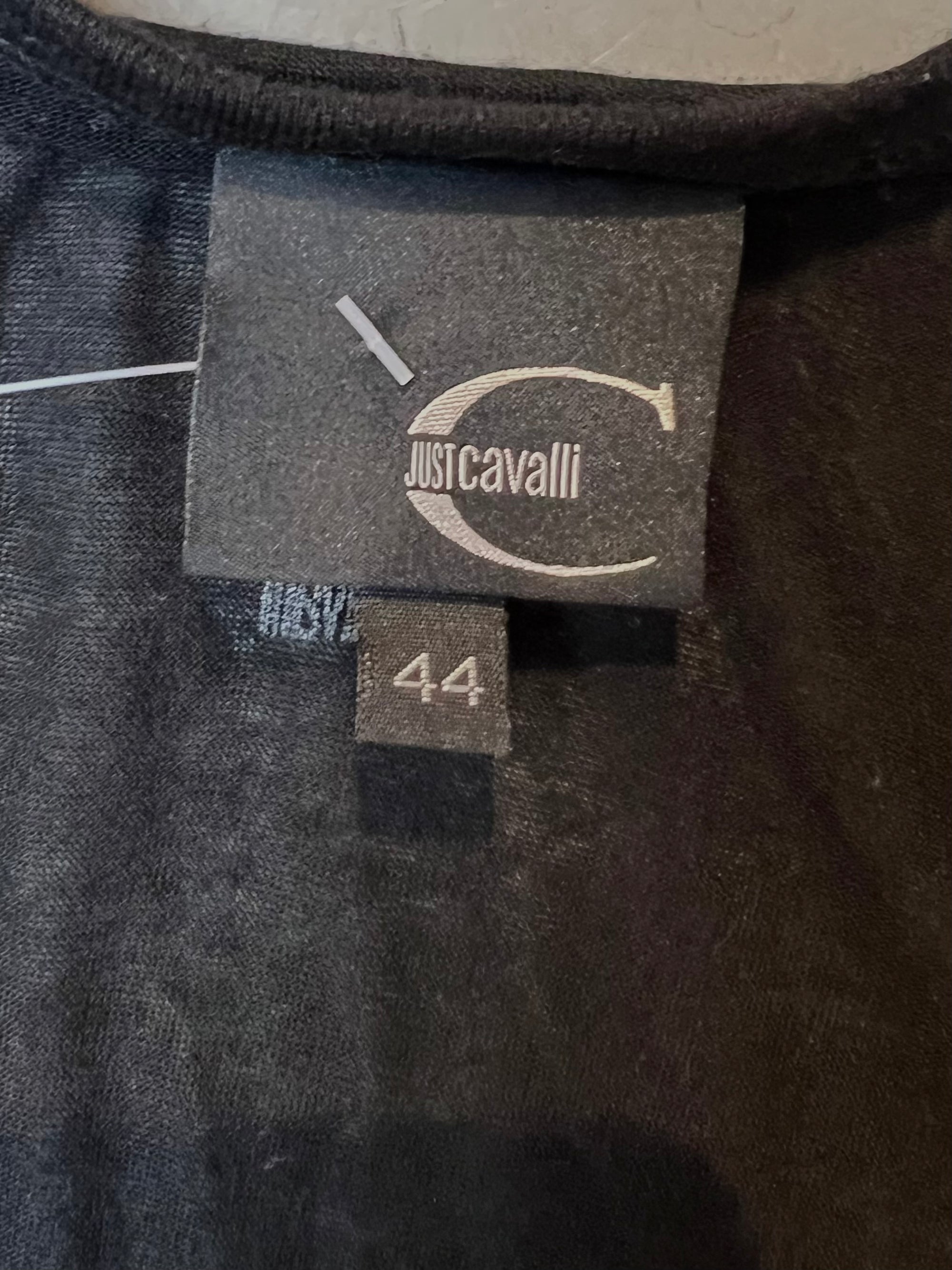 Langes schwarzes Top von Roberto Cavalli, Aufschrift “I love J.C” in glitzersteinen, produktbild vor grauem Hintergrund, nähere ansicht des Etiketts.
