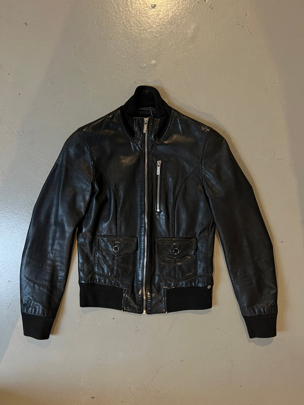 Produktbild von schwarzer Lederjacke vorne Auf grauem Boden 