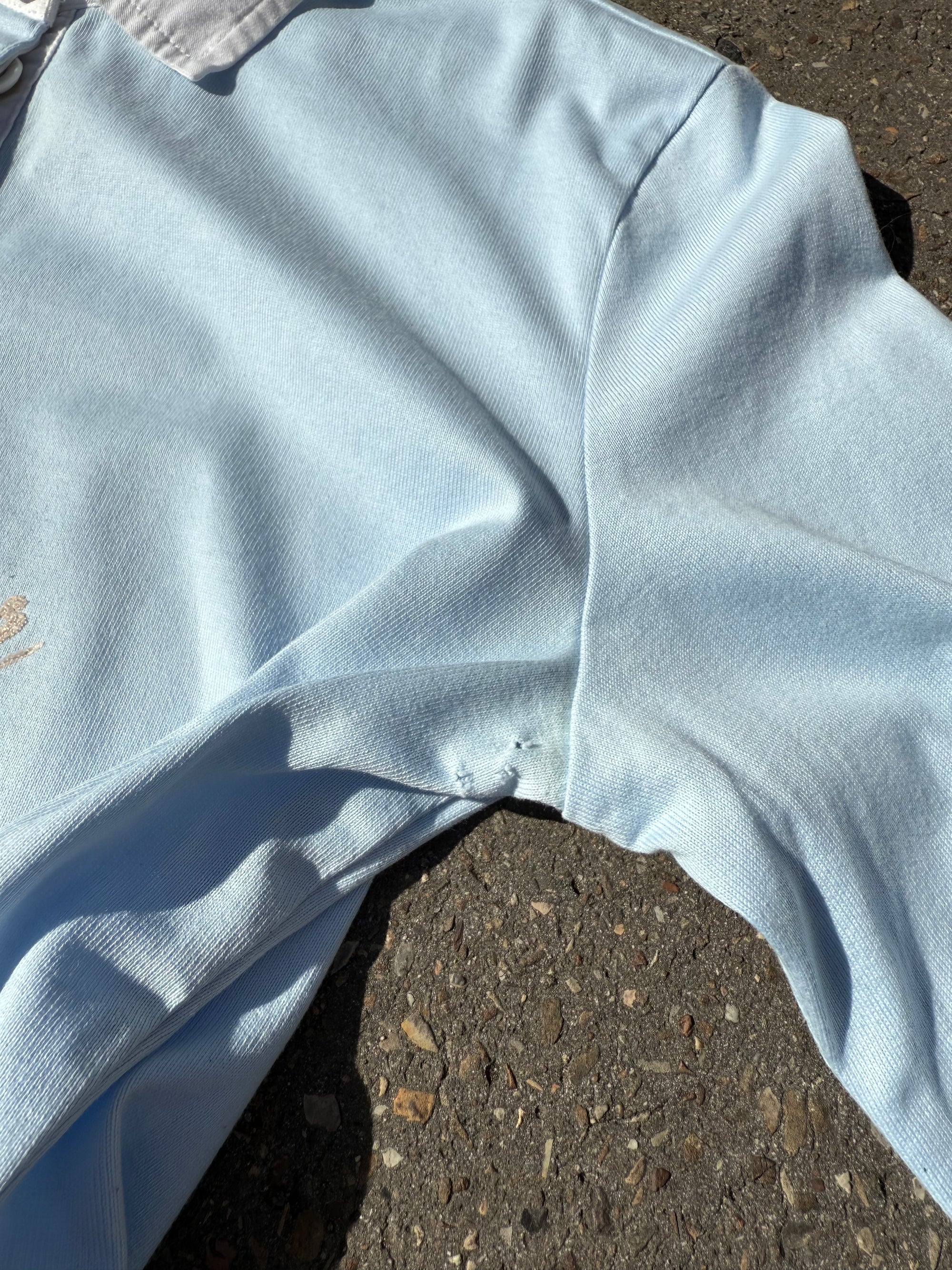 Ein babyblaues langärmliges Polo mit weißem Kragen und Hilfiger in Silber auf der Brust geschrieben 