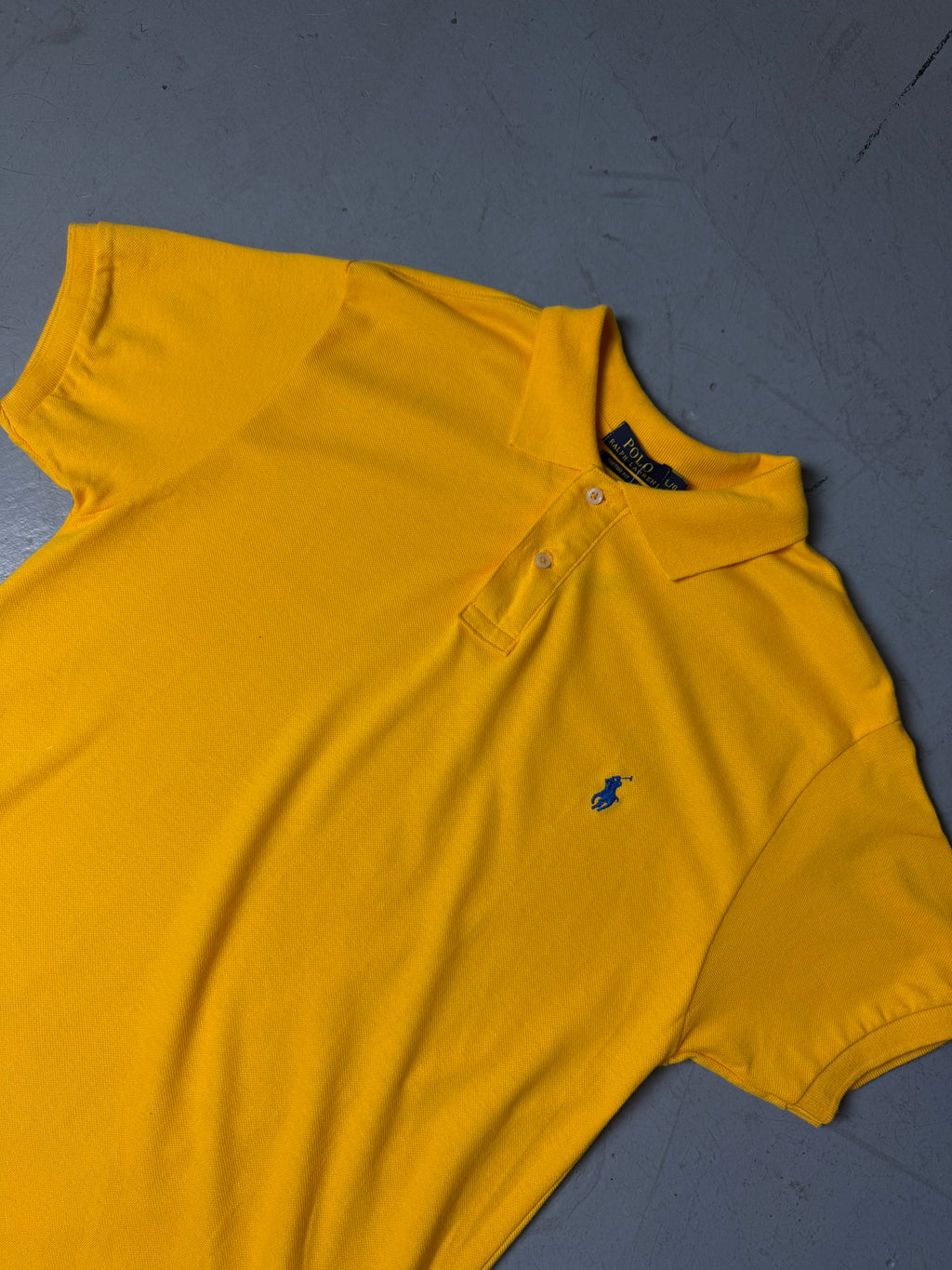 Ein gelbes Polo von Ralph Lauren mit blauem Reiter auf der Brust in L