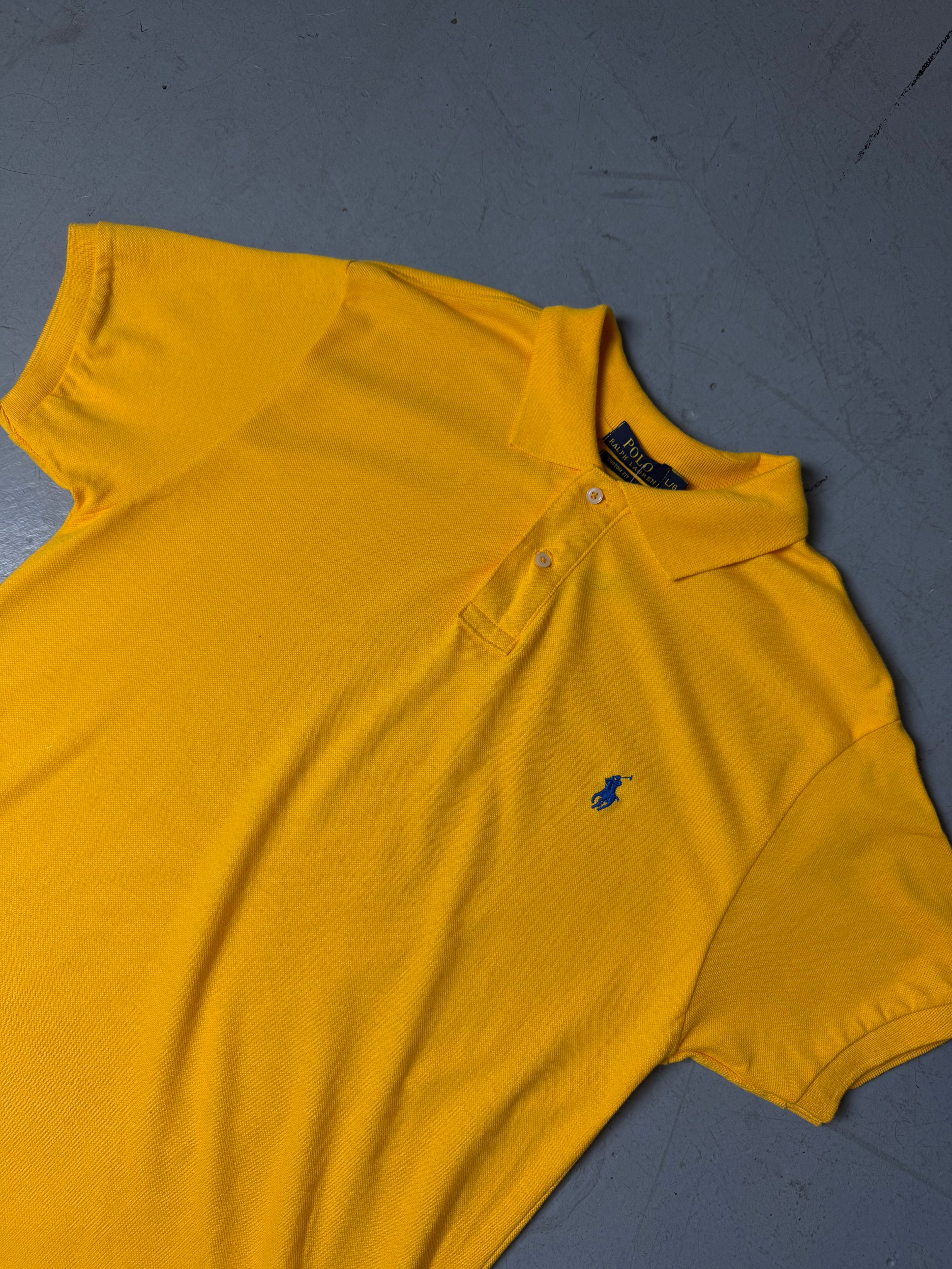 Ein gelbes Polo von Ralph Lauren mit blauem Reiter auf der Brust in L