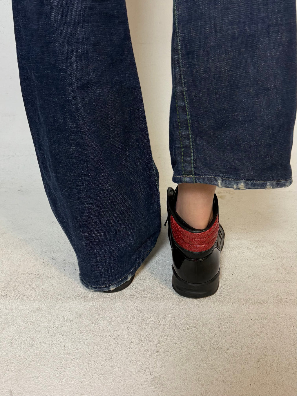 Schwarze gucci sneaker mit roten details hinten und roter sohle 