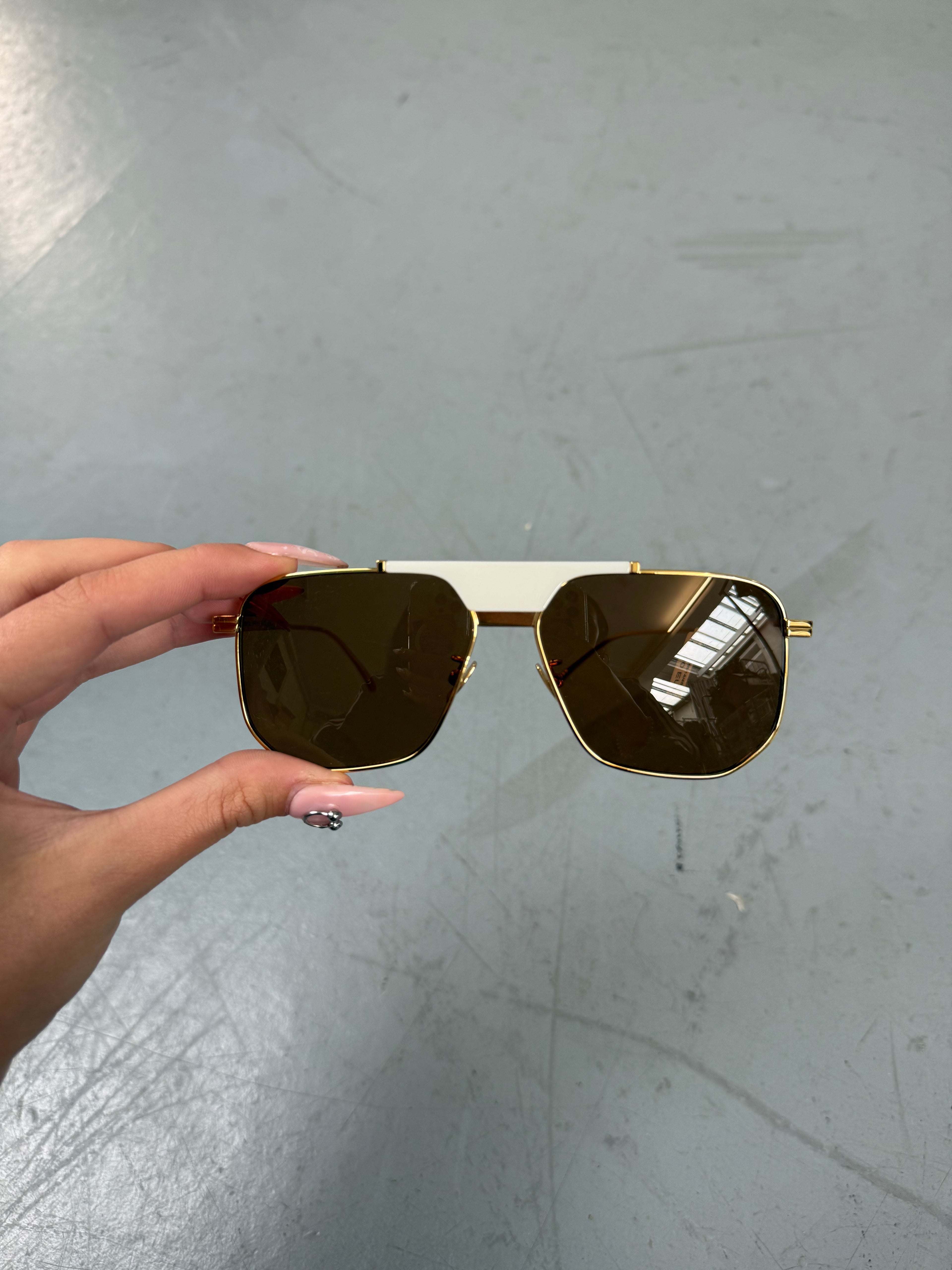 Eine weiß goldene Sonnenbrille mit großen Gläsern von Bottega veneta 