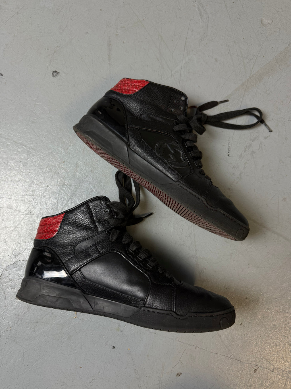 Schwarze gucci sneaker mit roten details hinten und roter sohle 