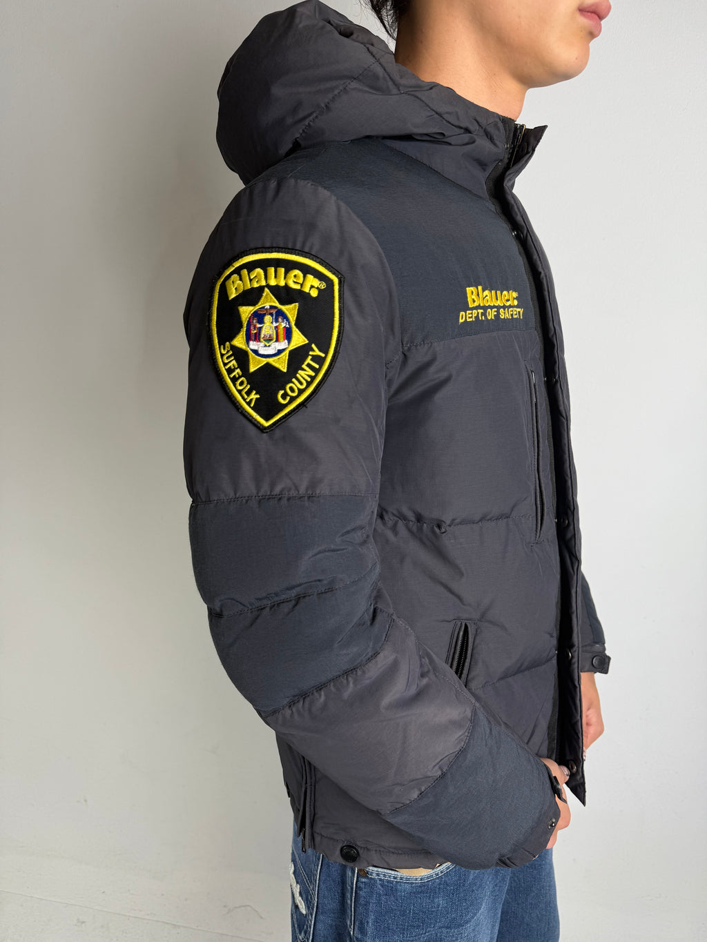 Detailliertes tragebild von Grauer Blauer Daunen Jacke in L vor grauer Wand