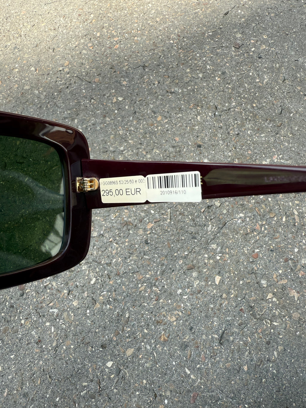 Eine burgunderrote Sonnenbrille von Gucci mit dem Logo in Gold an der Seite und großen quadratischen Gläsern