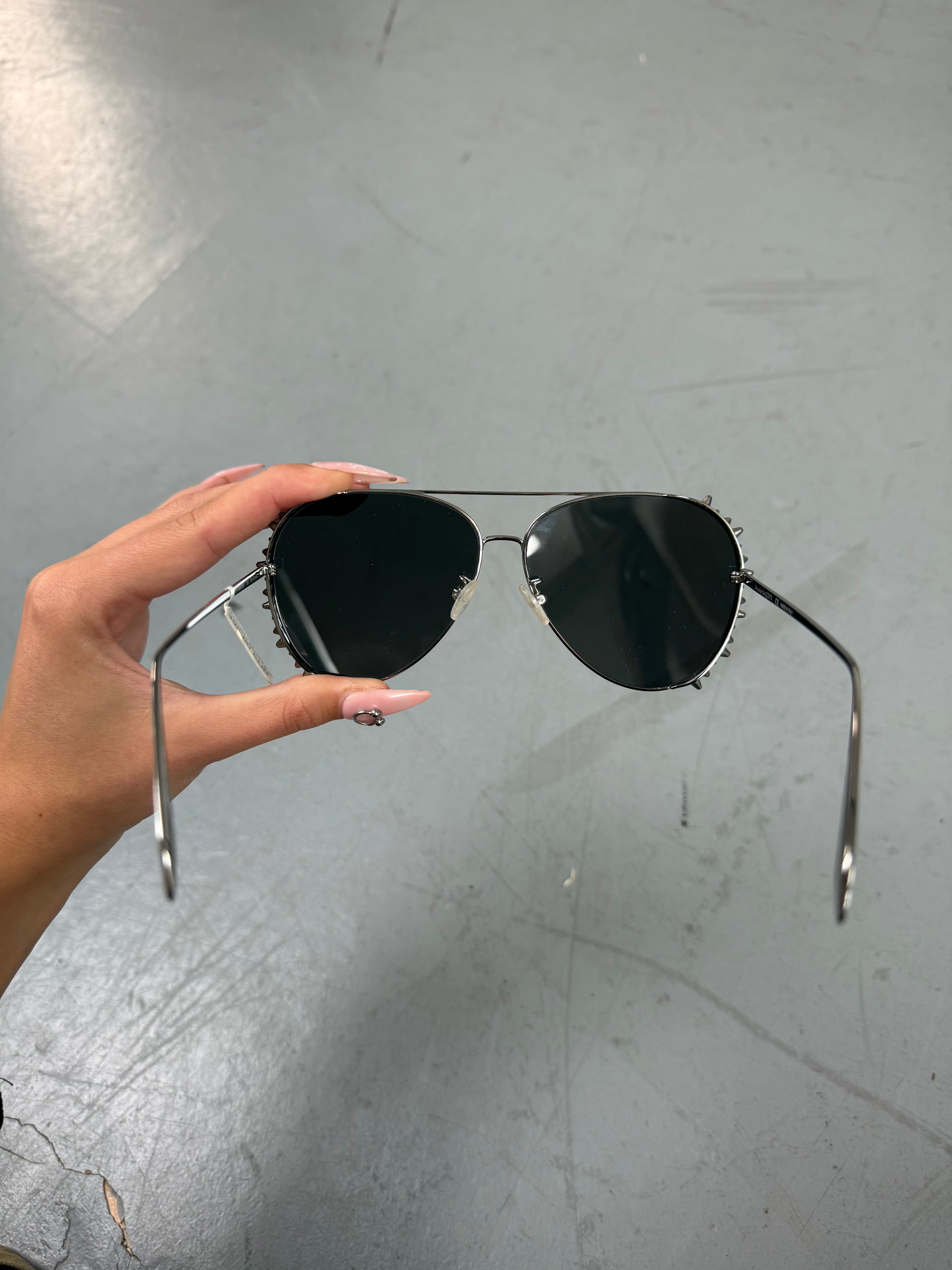 Eine Sonnenbrille von Alexander McQueen mit silbernen Nieten um die großen Gläser und dünnem Gestell 