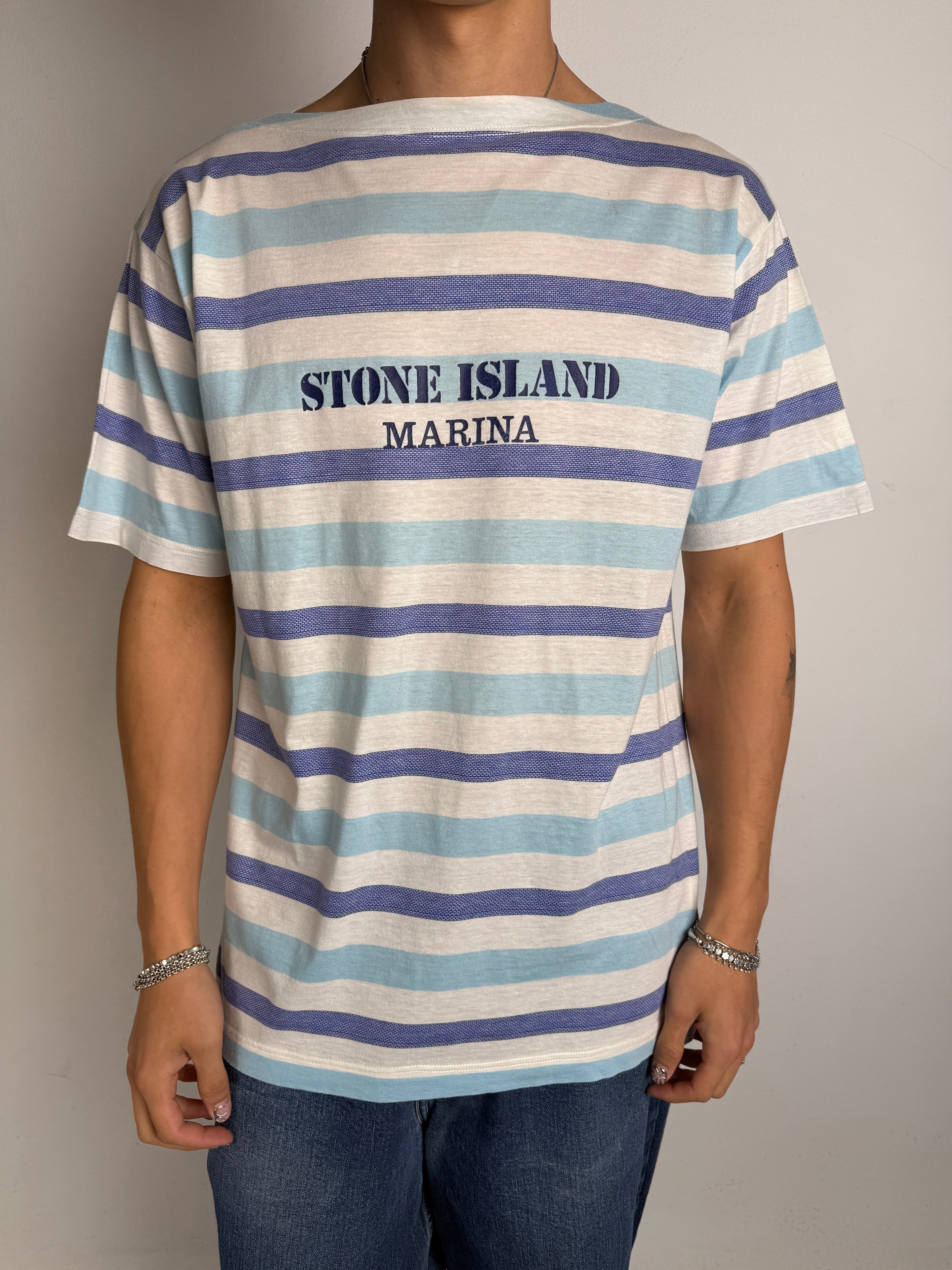 Tragebild von blau weis gestreiftem Stone Island Tshirt vor grauer Wand