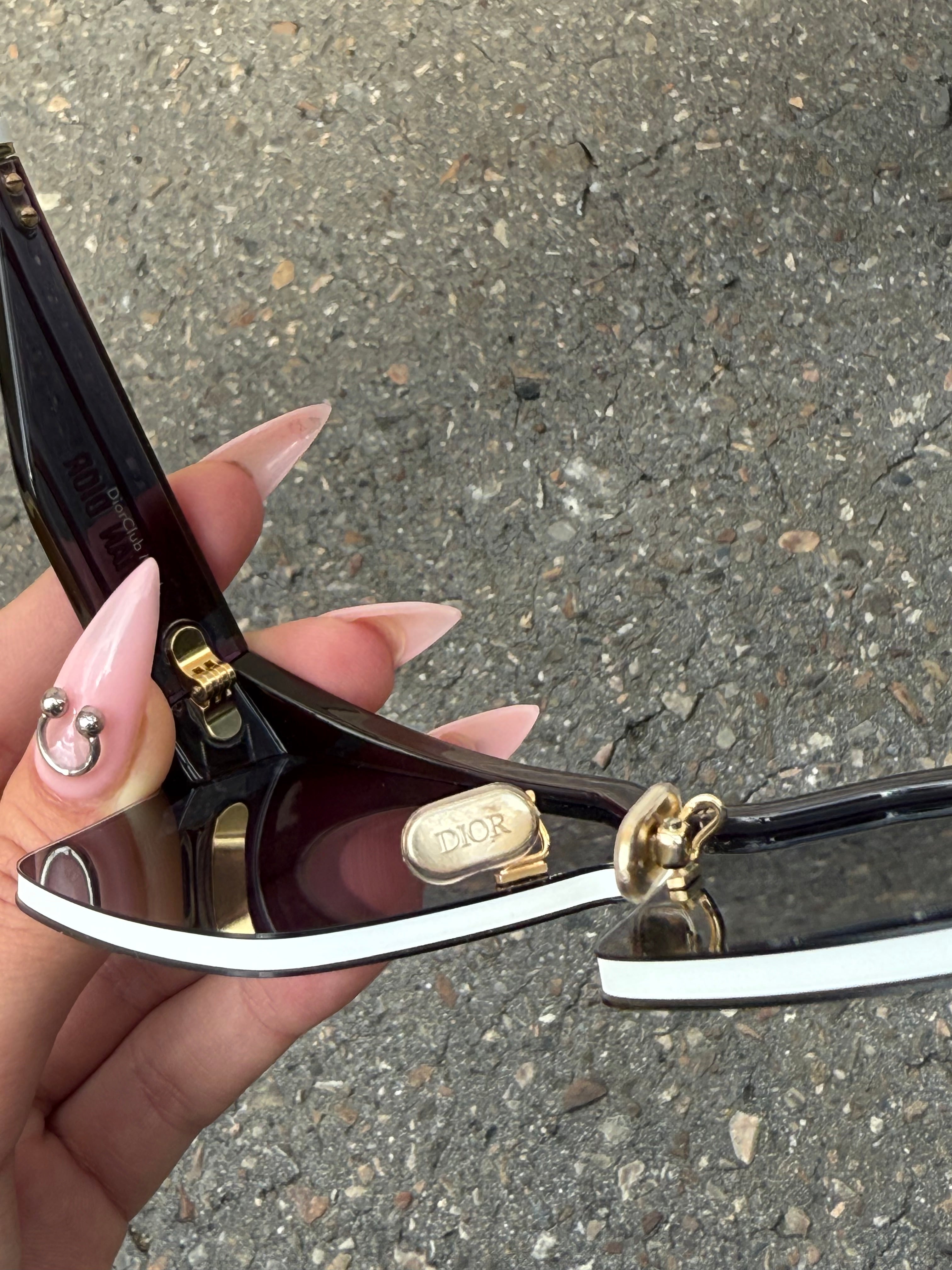 Eine schwarze Sonnenbrille von Dior mit dem Monogram auf den Gläsern und dem Markennamen auf den Bügeln