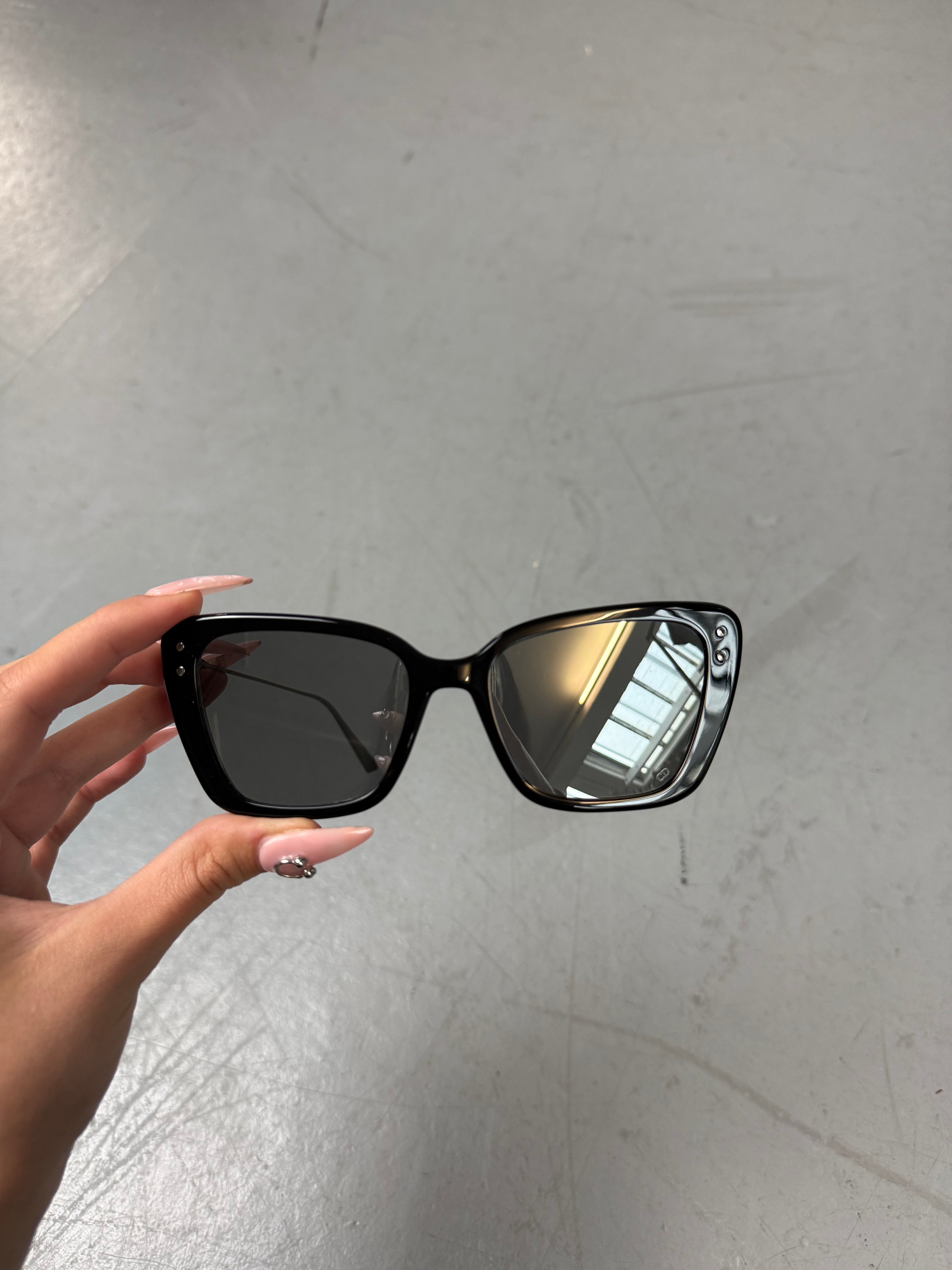 Eine schwarze Sonnenbrille von Dior mit dünnen Bügeln und die Gläser im cateye look 