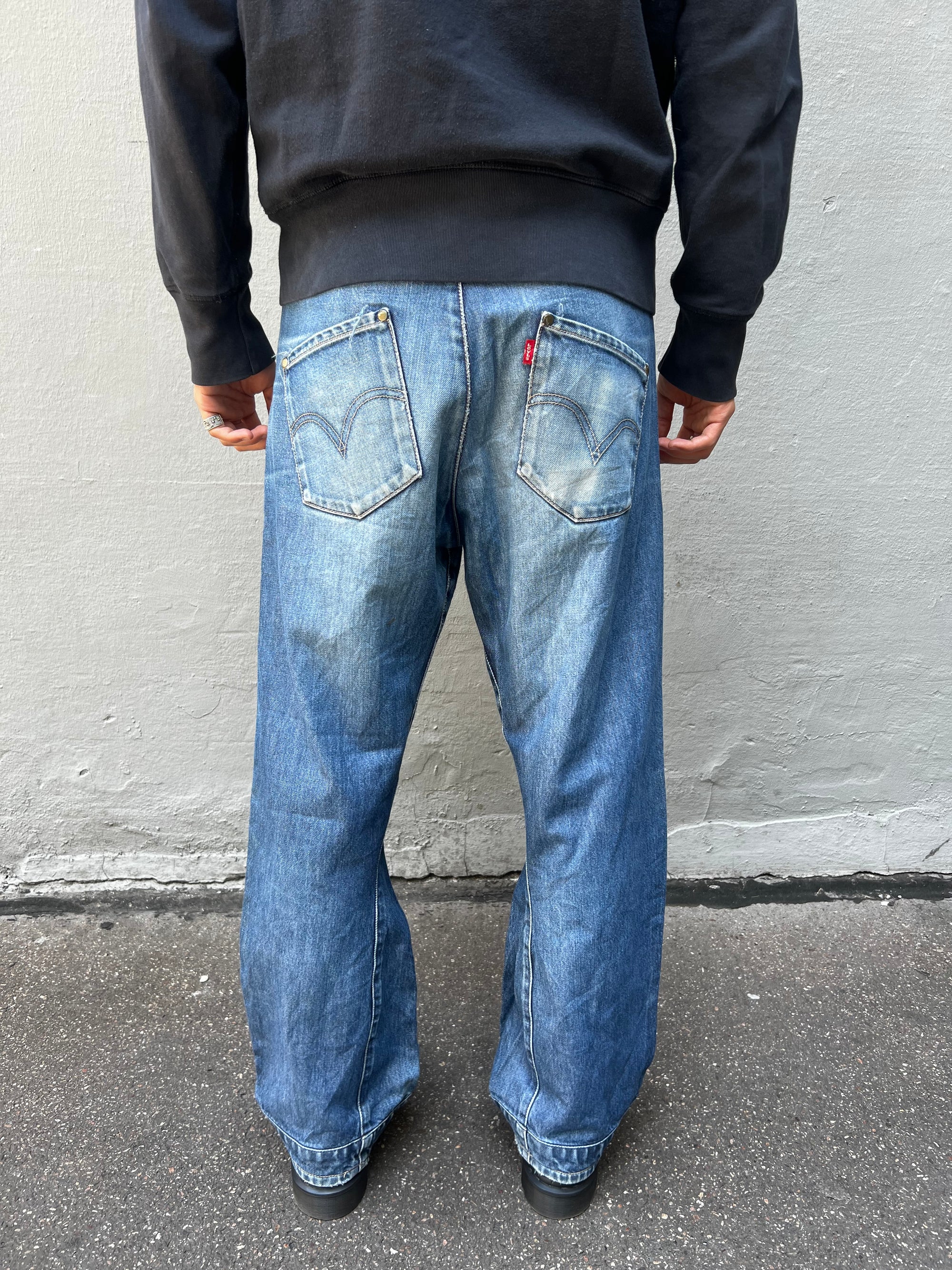 Tragebild von blauer Vintage Levis Hose, Größe M/L vor grauer Wand von hinten