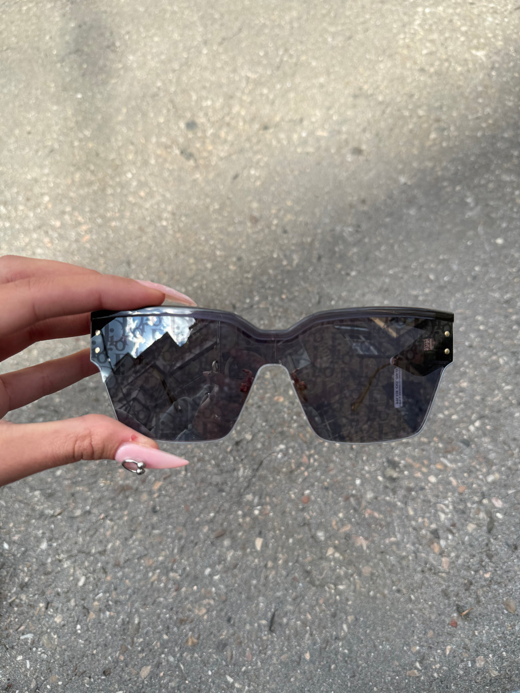 Eine schwarze Sonnenbrille von Dior mit dem Monogram auf den Gläsern und dem Markennamen auf den Bügeln