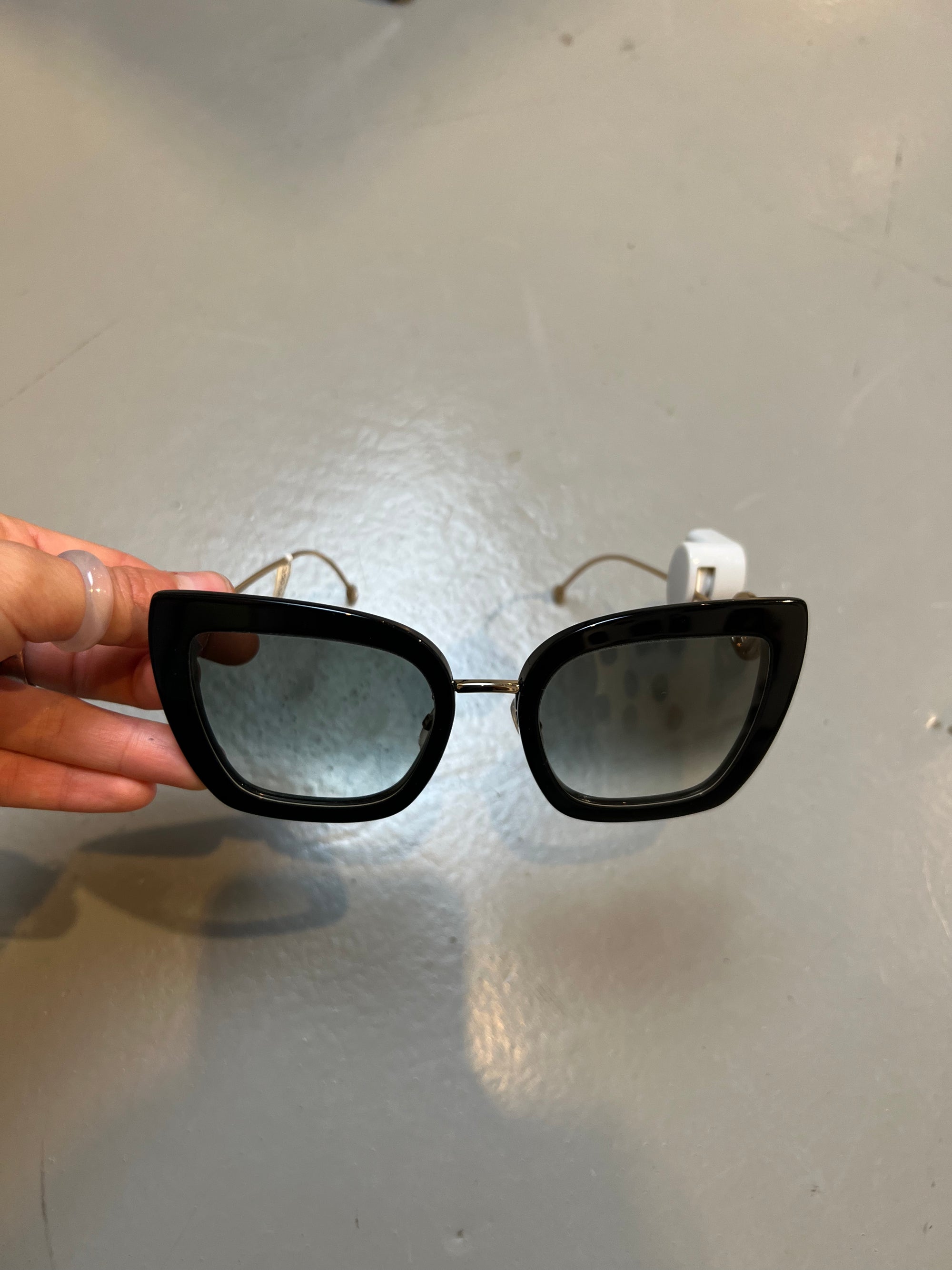Produktbild von einer schwarzen Fendi Sonnenbrille auf grauem Boden.