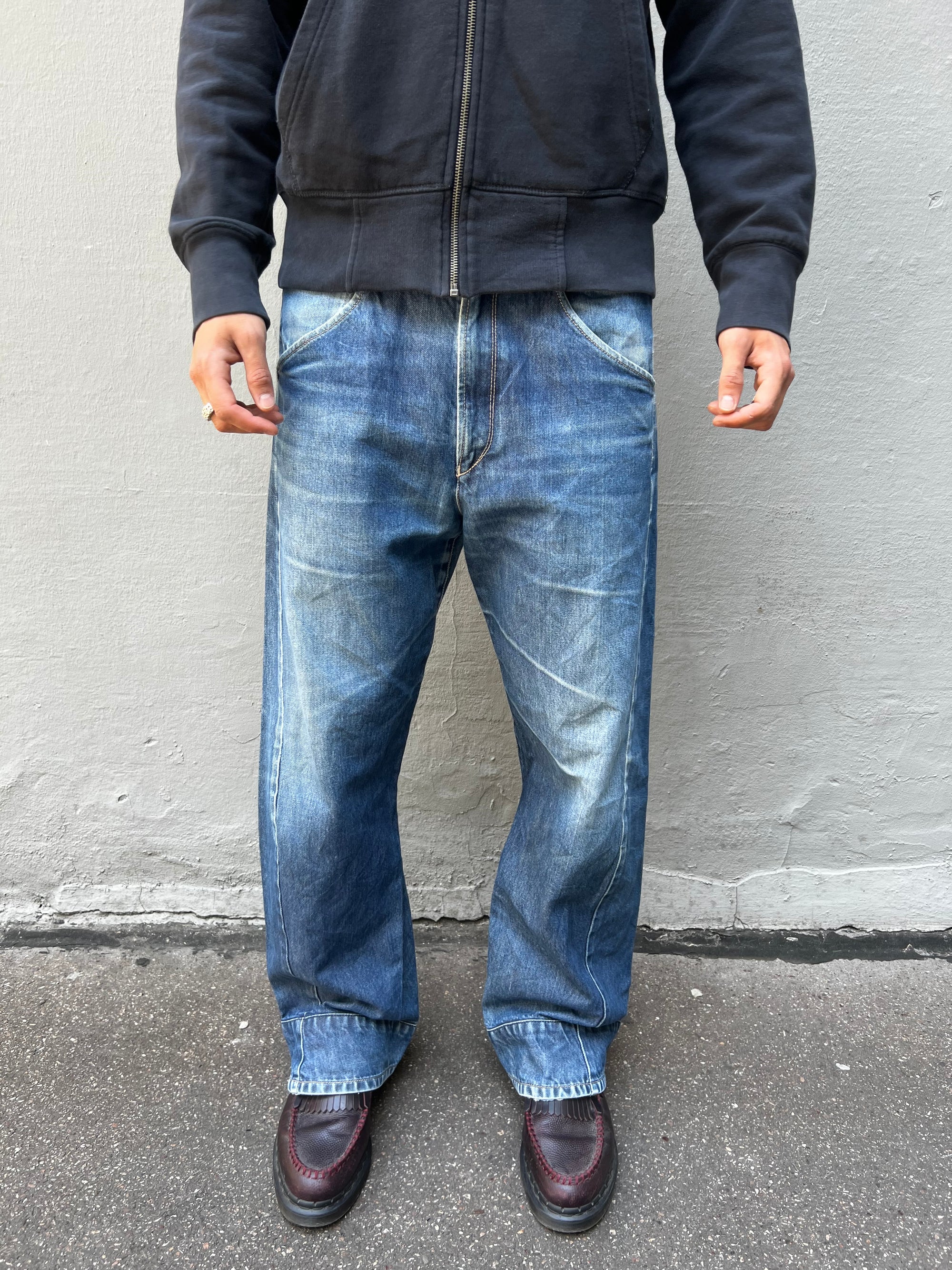 Tragebild von blauer Levis Hose, Größe M/L vor grauer Wand von vorne