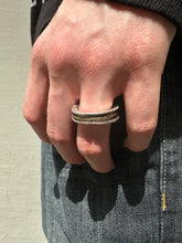 Laden Sie das Bild in den Galerie-Viewer, Tragebild vom Ringfinger von Ringsbyclausen Ring „Krater 3“ vor grauer Wand