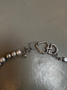 Detailliertes Produktbild von Xullery Cross Grey Pearl Necklace auf grauem Boden.