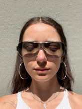Laden Sie das Bild in den Galerie-Viewer, Weibliches Model trägt Dolce&amp;Gabbana Sonnenbrillle mit schwarzem Bügel und 2000er Stil vor grauer Wand.