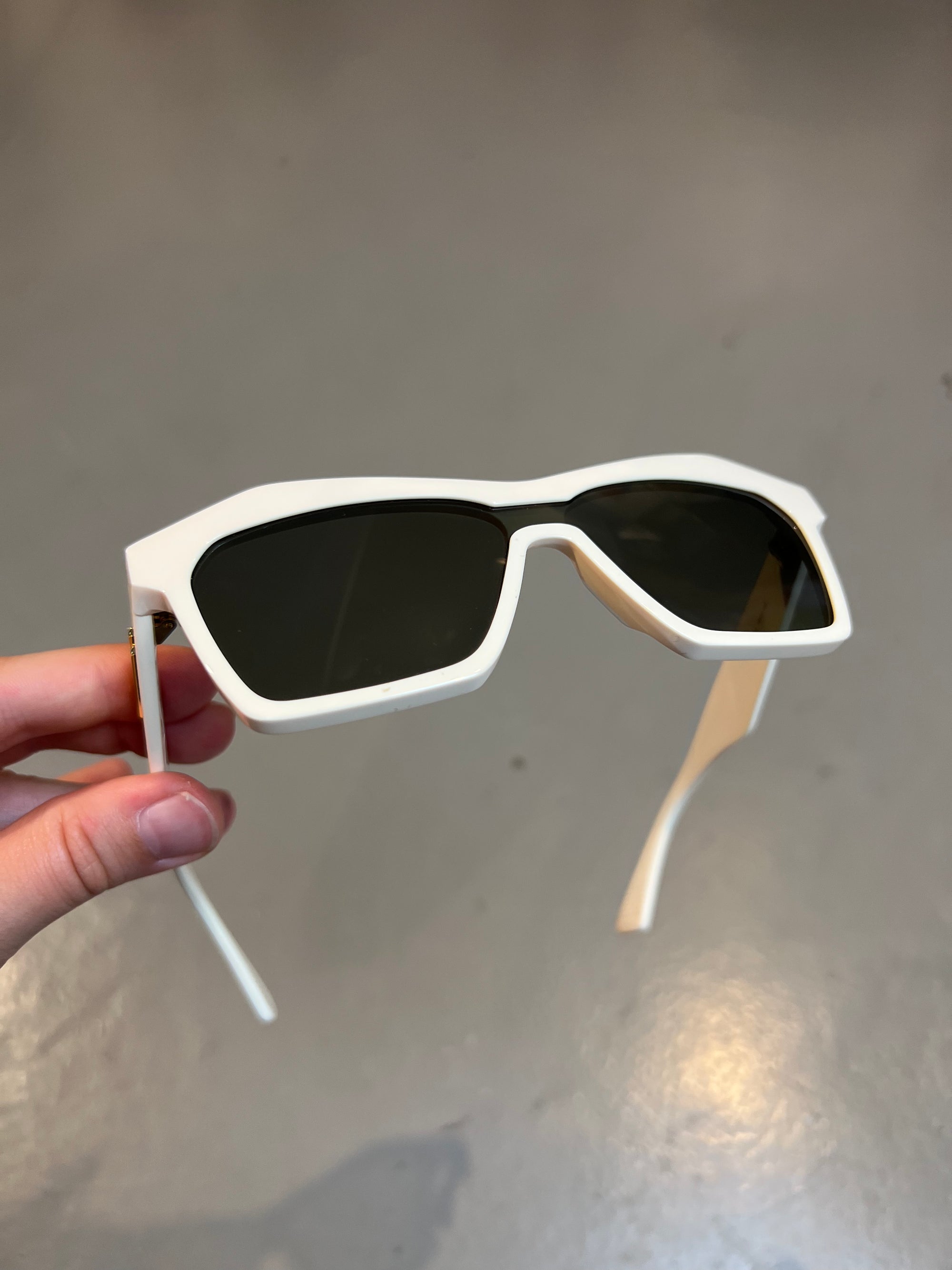 Produktbild von einer Bottega Veneta Sonnenbrille mit beigen Gehäuse vor einem grauen Hintergrund. 