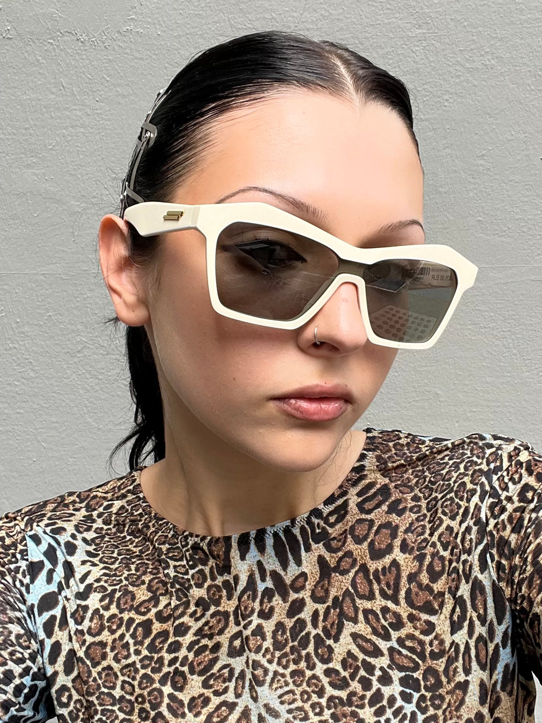 Tragebild von einer Bottega Veneta Sonnenbrille mit beigen Gehäuse vor einem grauen Hintergrund. 