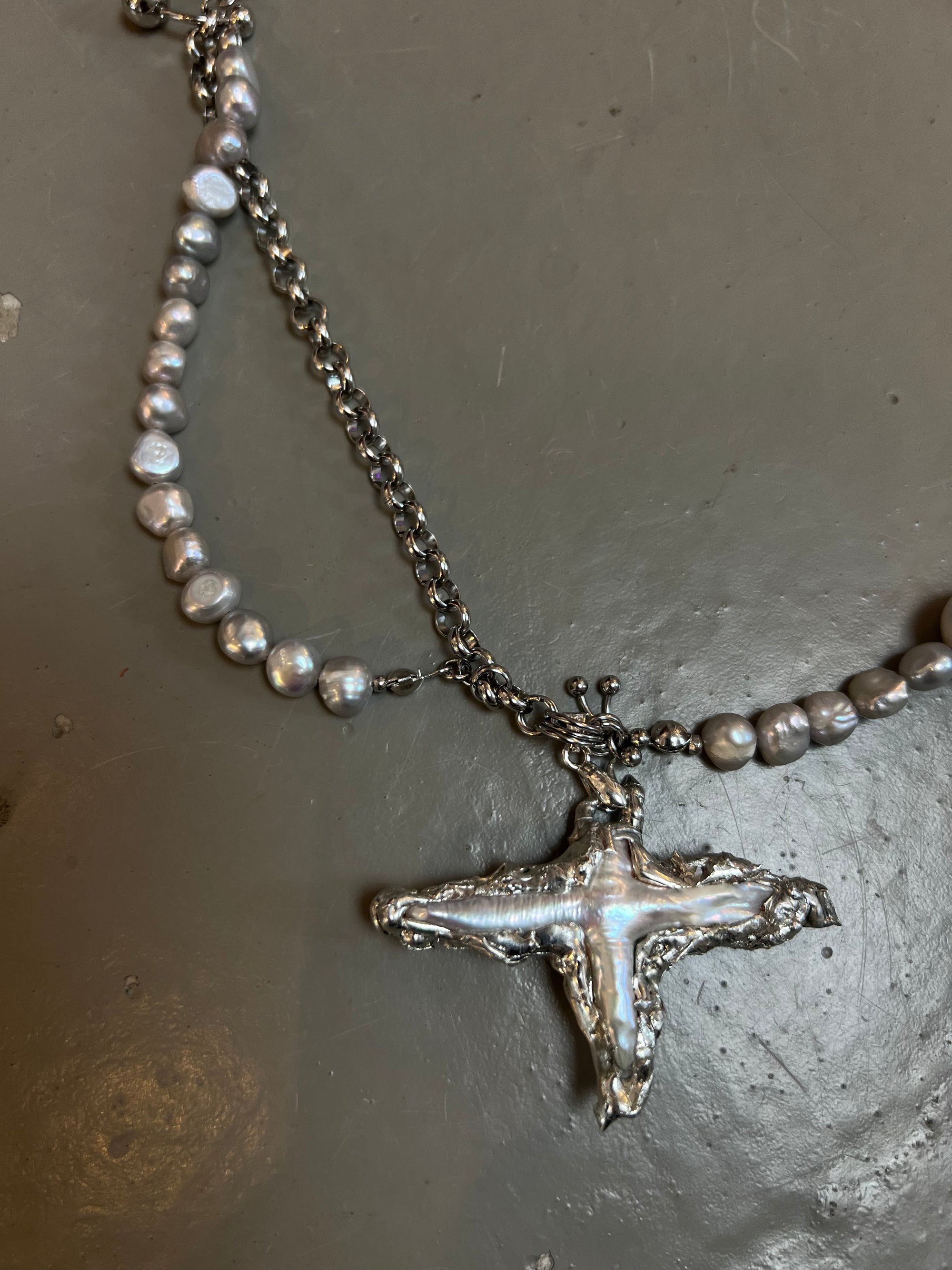 Produktbild von Xullery Cross Grey Pearl Necklace auf grauem Boden.