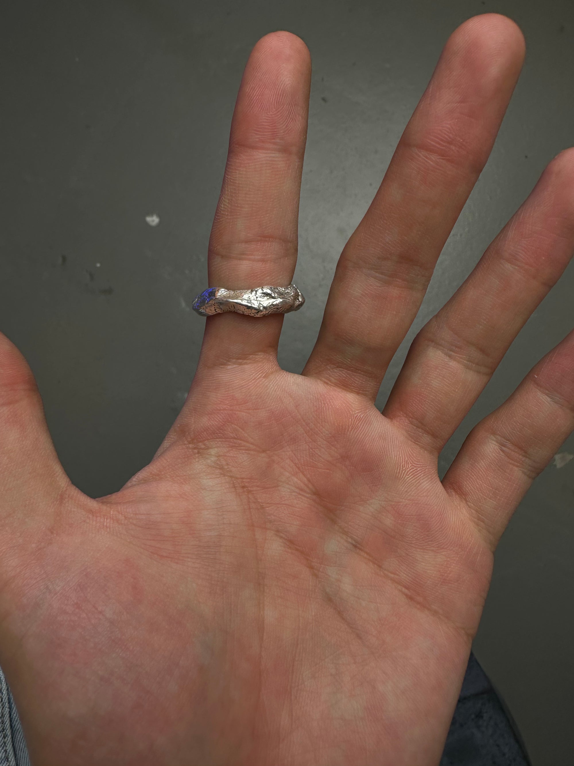 Ringsbyclausen Ring „Handgeformt“ Tragebild vom Zeigefinger vor grauem Boden