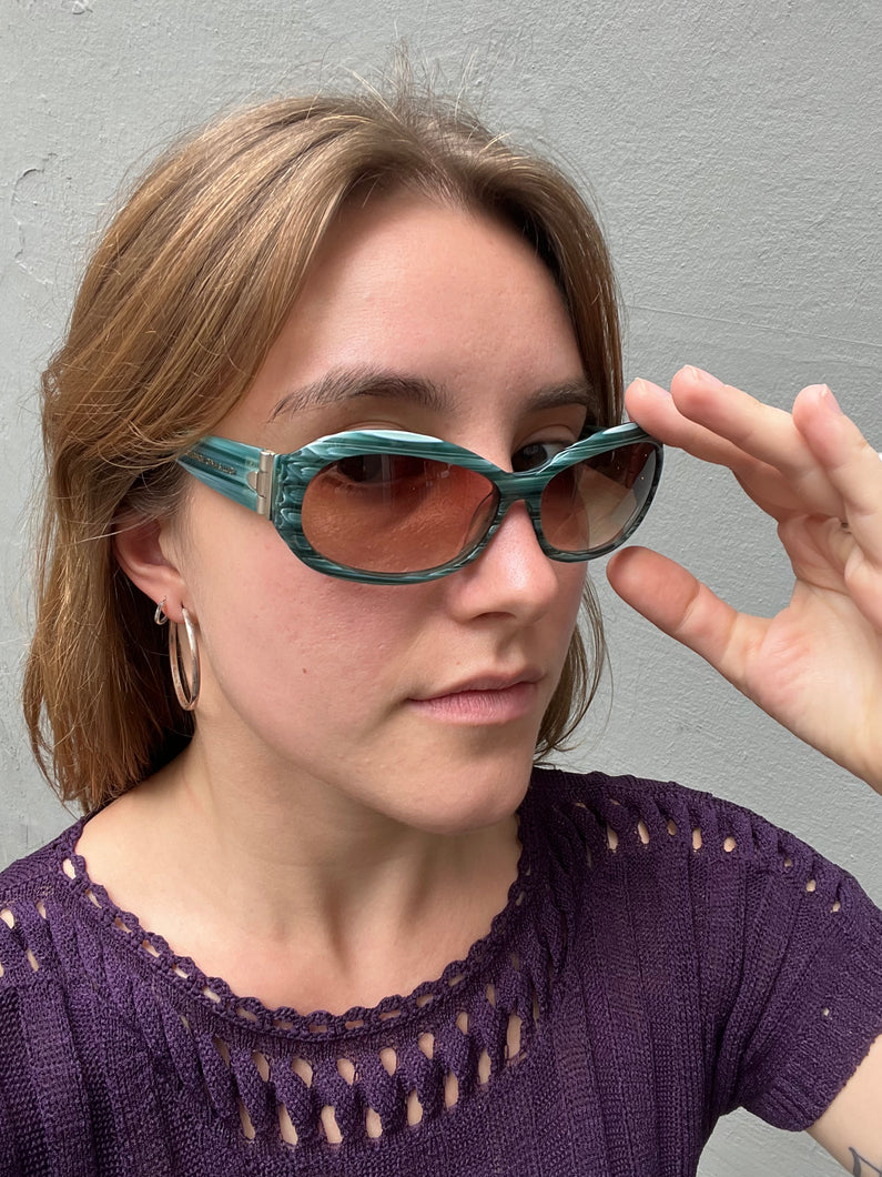 Tragebild von einer Vintage George Gina & Lucy Sonnenbrille vor einem grauen Hintergrund.