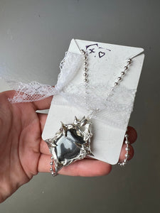 Produktbild von einer silbernen Halskette mit einem schwarzen Hematite Anhänger von Xullery vor einem grauen Hintergrund.