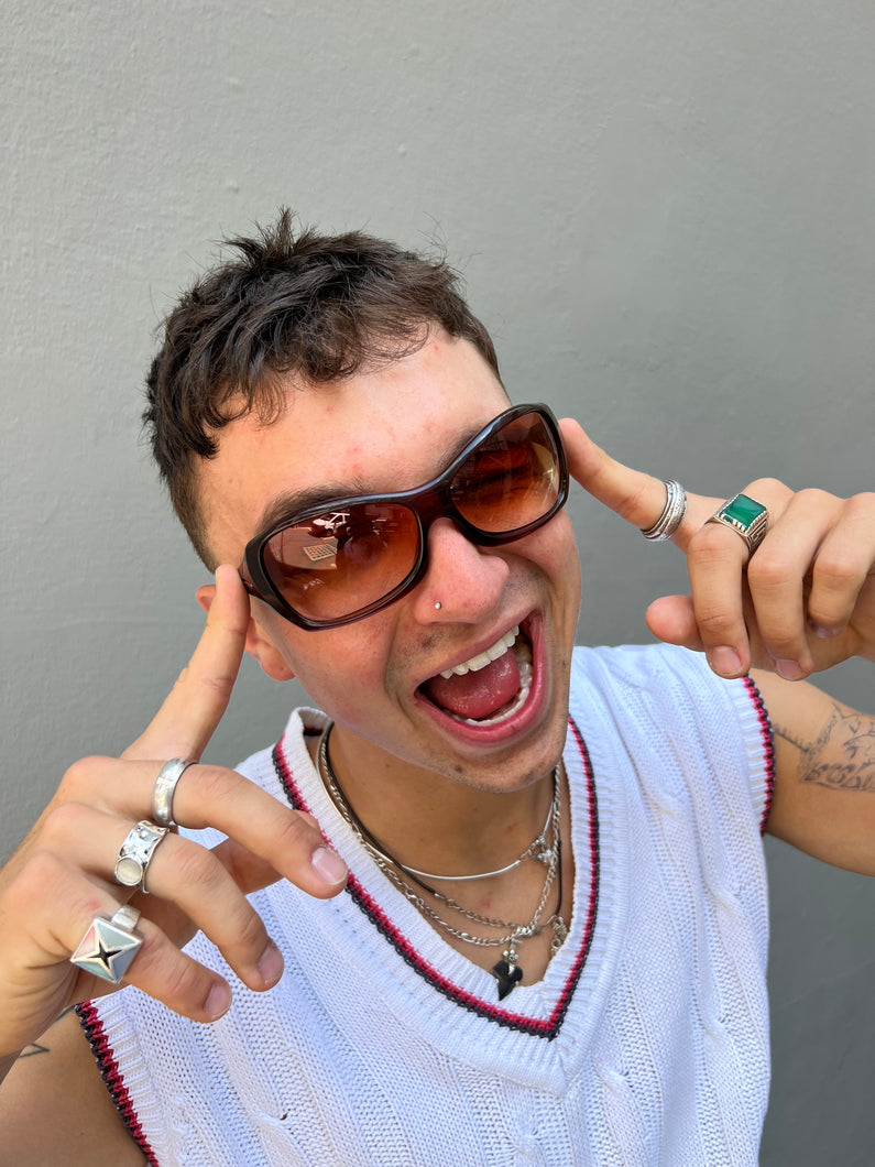 Tragebild von einer Braunen Oakley Sonnenbrille vor einer Grauen Wand.