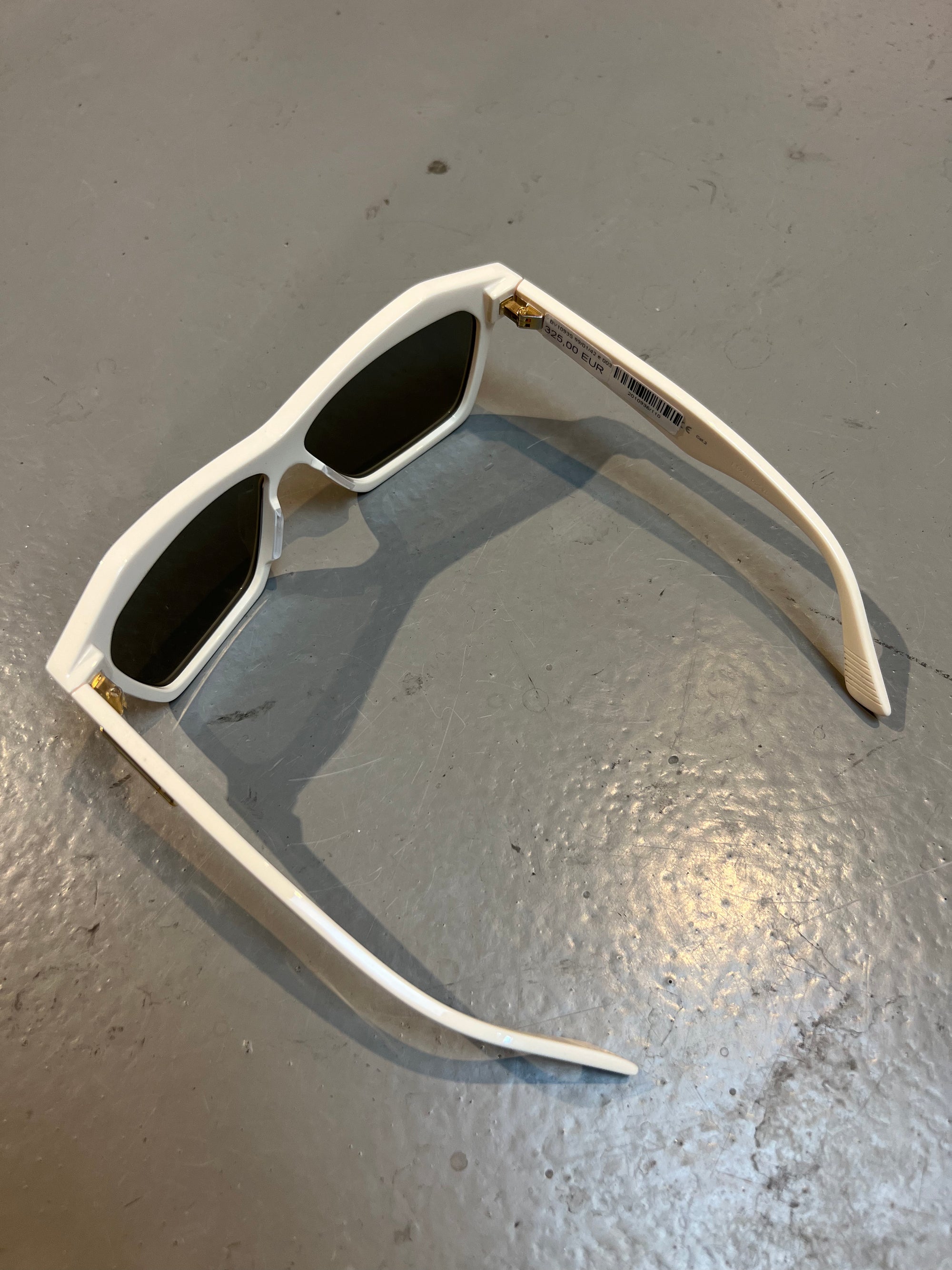 Produktbild von einer Bottega Veneta Sonnenbrille mit beigen Gehäuse vor einem grauen Hintergrund. 