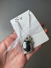 Laden Sie das Bild in den Galerie-Viewer, Produktbild von einer silbernen Halskette mit einem schwarzen Hematite Anhänger von Xullery vor einem grauen Hintergrund.
