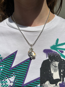 Tragebild von Xullery Dragon Egg 2 Necklace vor einem grauen Hintergrund.