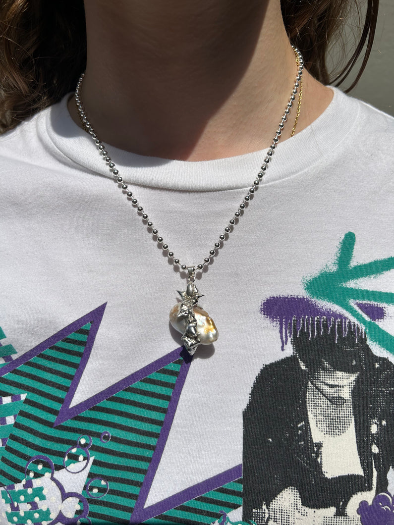 Tragebild von Xullery Dragon Egg 2 Necklace vor einem grauen Hintergrund.