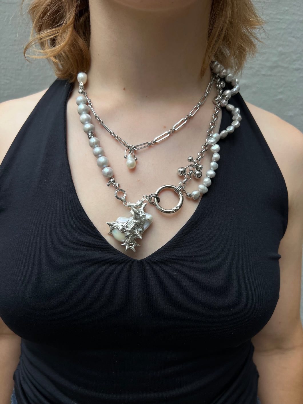 Xullery Grey Pearl Necklace DNA Tragebild von vorne vor grauer Betonwand