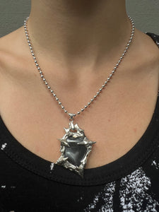 Tragebild von einer silbernen Halskette mit einem schwarzen Hematite Anhänger von Xullery vor einem grauen Hintergrund.
