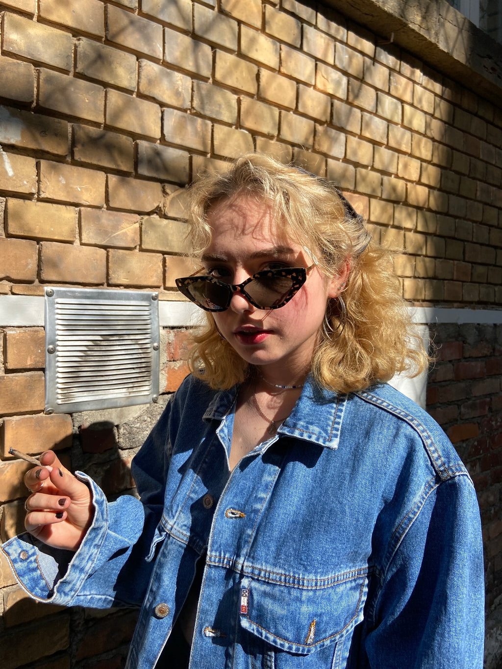 Tragebild der Mykita Sunglasses leo gold flexible von vorne vor Krachel Hintergrund.