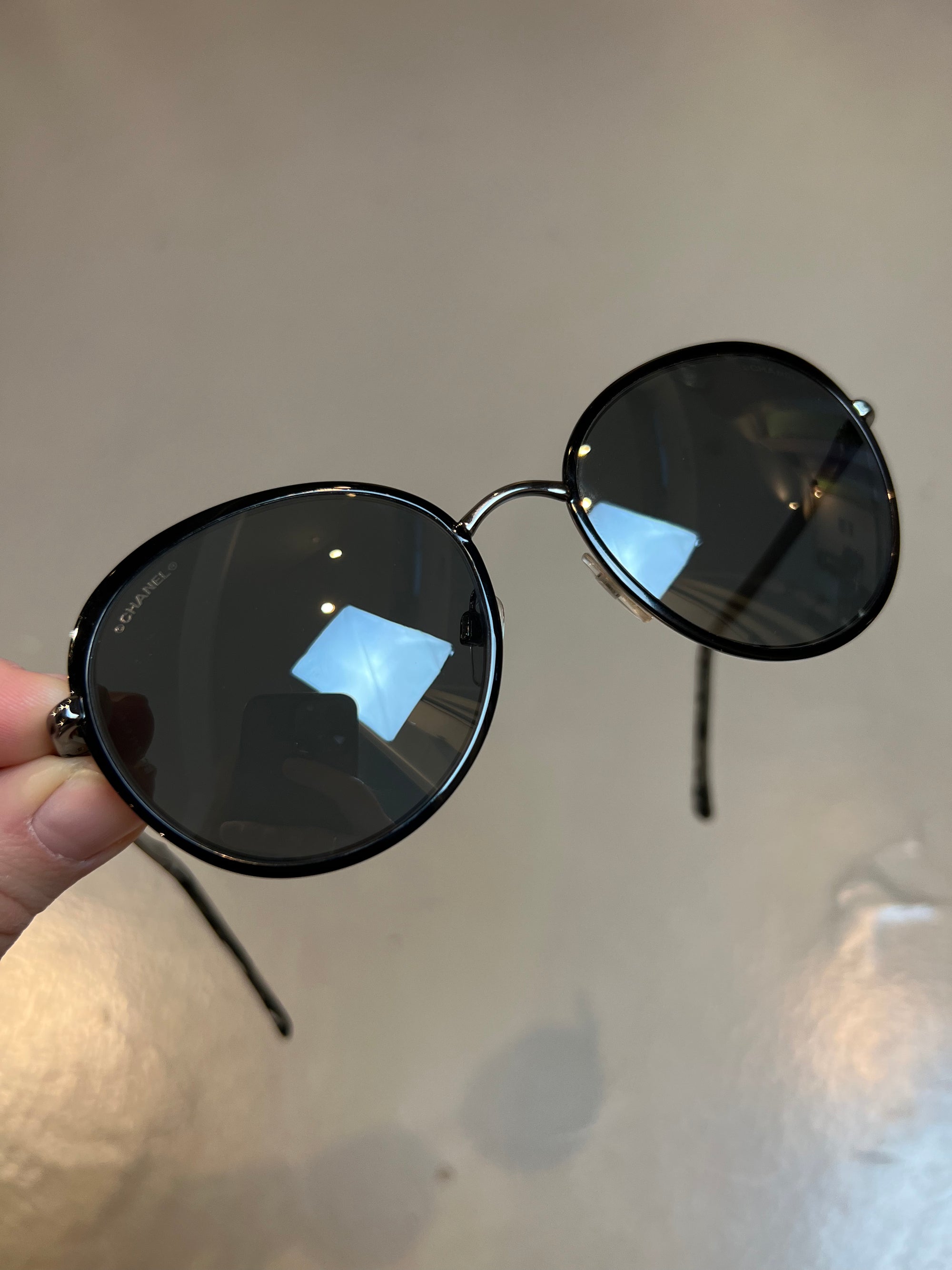 Produktbild einer runden Chanel Sonnenbrille in schwarz vor grauem Hintergrund.