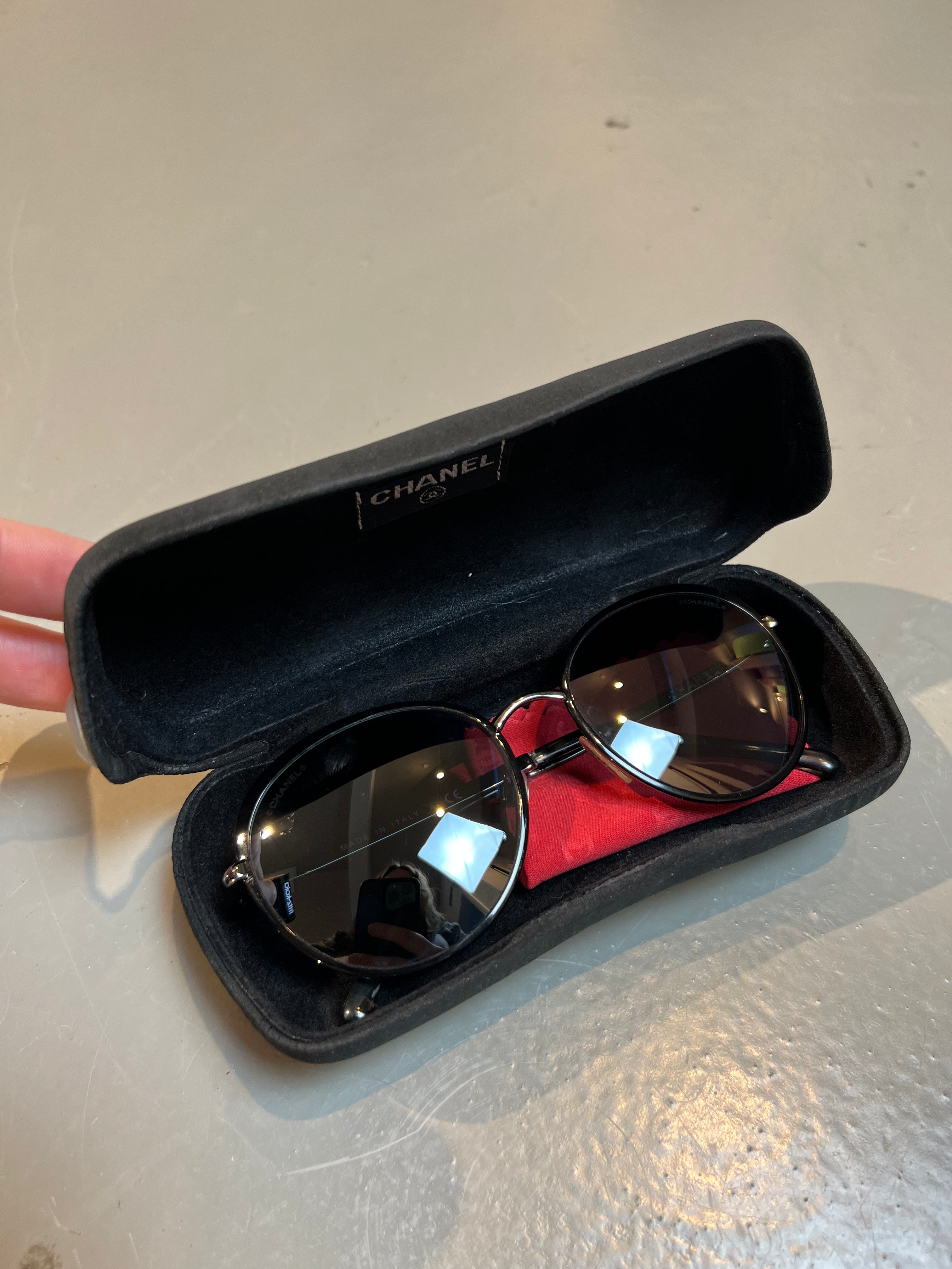 Produktbild einer runden Chanel Sonnenbrille in schwarz vor grauem Hintergrund.